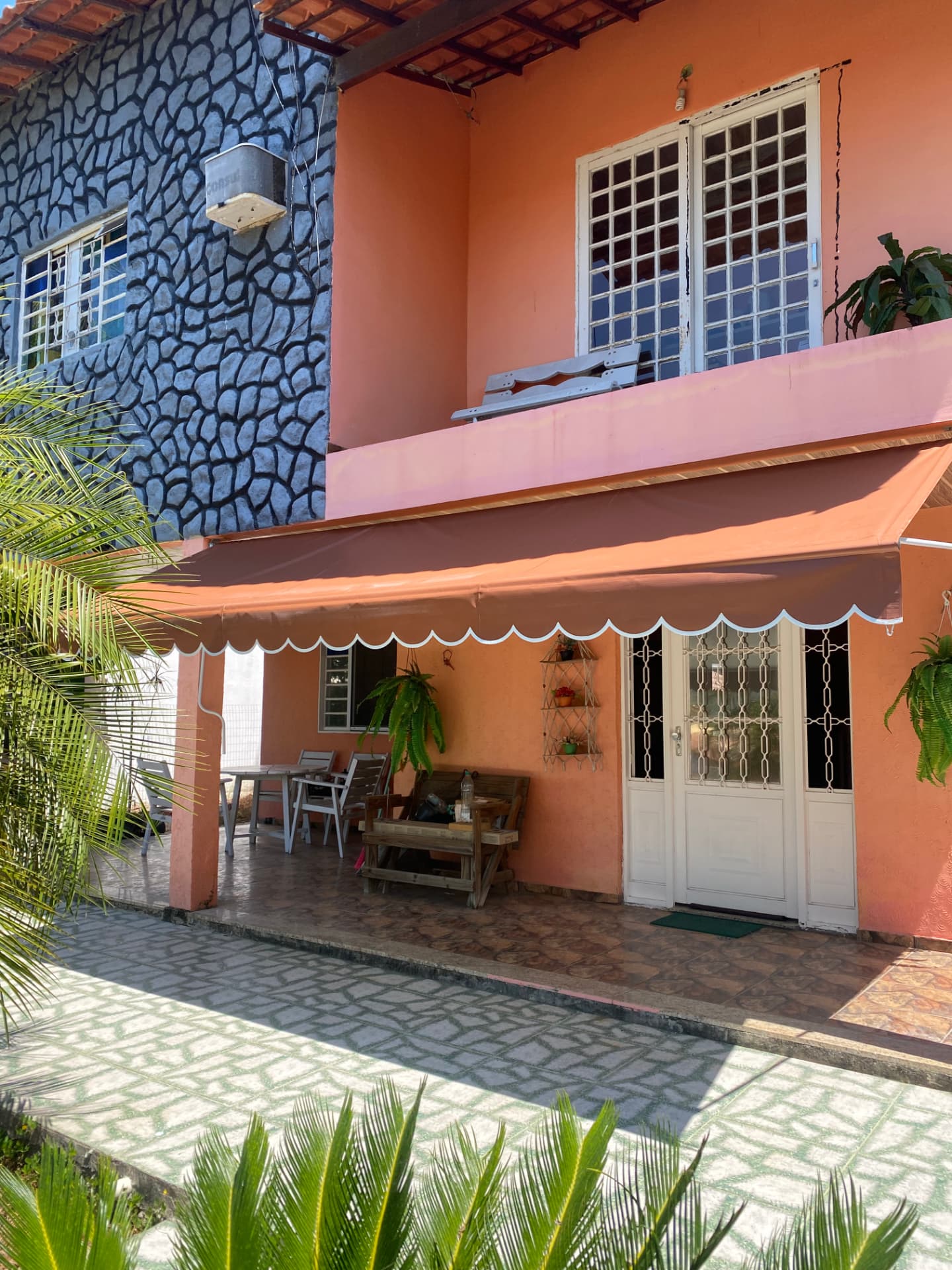 Toldo retrátil instalado na entrada de casa com varanda