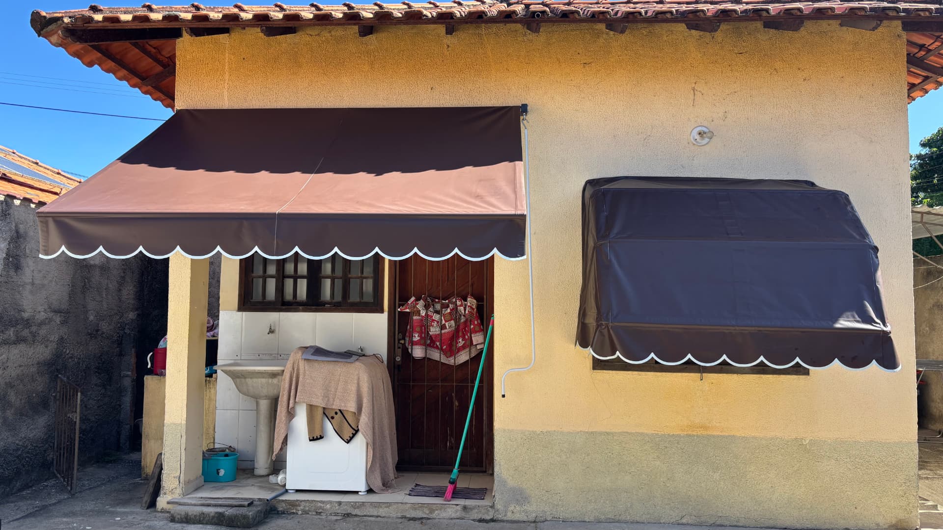 Casa com toldo retrátil marrom e capota de janela em São Gonçalo